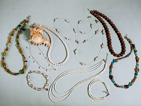 On left & far right: Antique beads in earth tones both $28.00 Sterling Necklace with Rose Quartz squares $30.00 Bracelet $25.00 Illusion Necklace $18.00 Bracelet $7.95 Anklet $12.95 Fresh Water Pearls  3-string Necklace $58.00 Bracelet $34.00 On top right:  Sunstone/Goldstone beads $32.00
